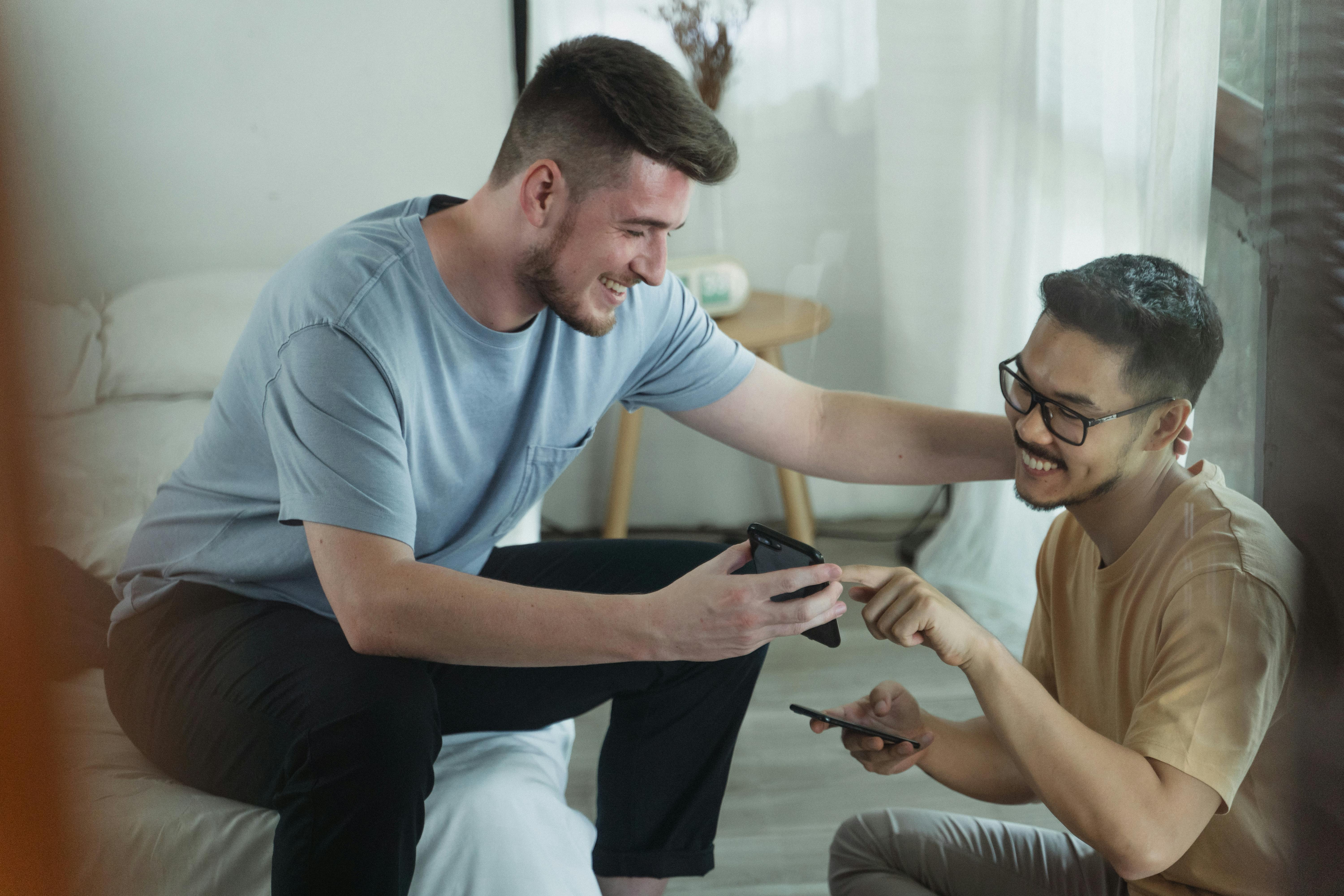 Smiling friends enjoying time together indoors sharing smartphone content.